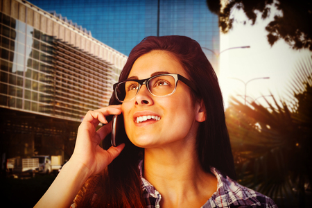 Close up of young woman talking on phone against front side of buildingsの写真素材