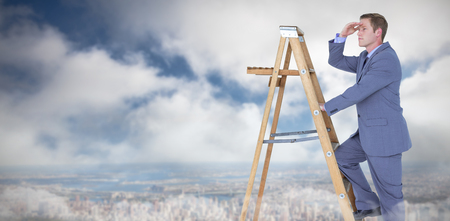 Businessman looking away while climbing on ladder against blue sky with cloudsの写真素材