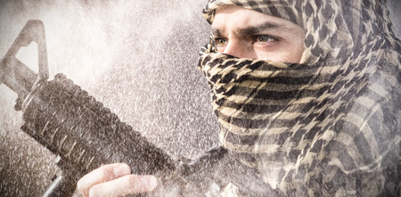 Close up of soldier with rifle looking away against black wall