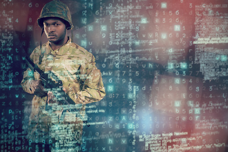 Portrait of confident soldier holding rifle against abstract black roomの写真素材