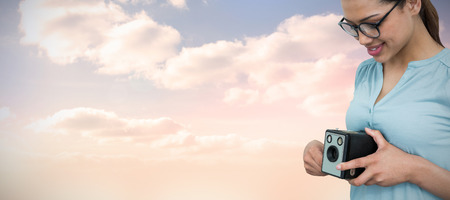 Mid section of happy female photographer holding vintage camera  against colored sky with clouds