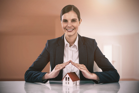 insurer protecting a house by his hands against bright room with wooden floorの写真素材
