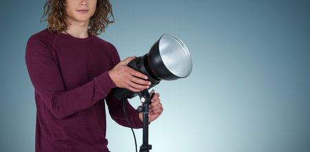 Portraot of young photographer holding focus light against grey vignetteの写真素材