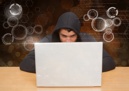 Digital composite of Hacker using a laptop in front of digital orange backgroundの写真素材