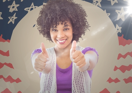 Digital composite of Millennial woman smiling and giving two thumbs up against hand drawn american flag with flareの写真素材