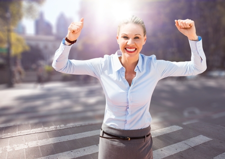 Digital composite of Business woman hands in air on blurry street with flaresの写真素材