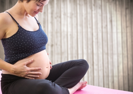 Digital composite of Pregnant woman meditating against blurry wood panel