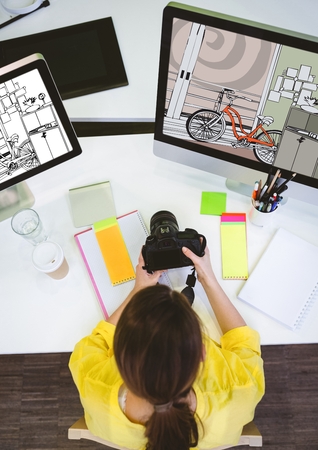 Digital composite of young photographer working on the computers on new designs and with cameraの写真素材