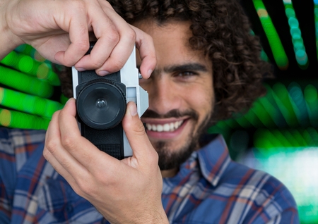 Digital composite of happy photographer taking a photo with vintage camera. Green blurred lights behindの写真素材