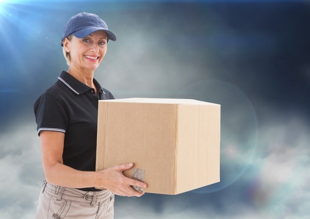 Digital composite of Middle aged delivery woman with box against clouds and flares