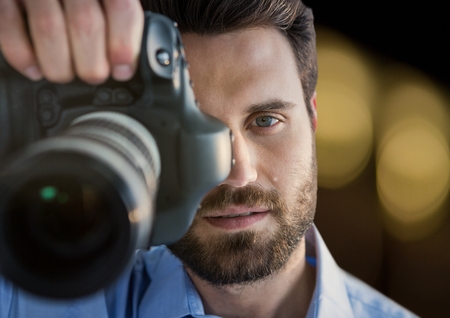 Digital composite of photographer taking a photo (foreground). Blurred lights on back