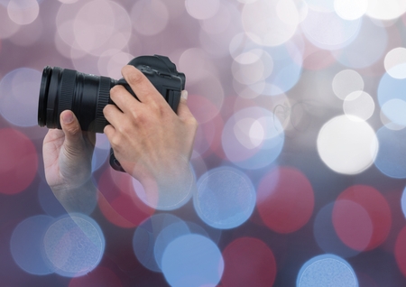 Digital composite of hands holding a camera against glowing background