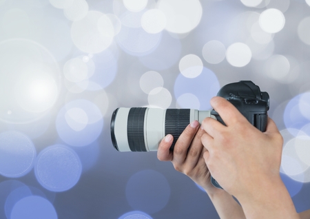 Digital composite of hands holding a camera against glowing background