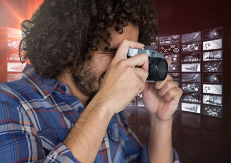 Digital composite of photograph taking picture with his camera against screensの写真素材