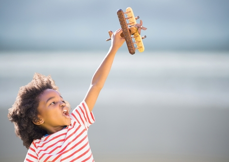 Digital composite of Boy with toy plane against blurry beach
