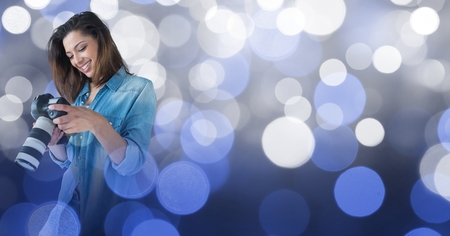 Digital composite of Photographer looking at her camera against glowing background