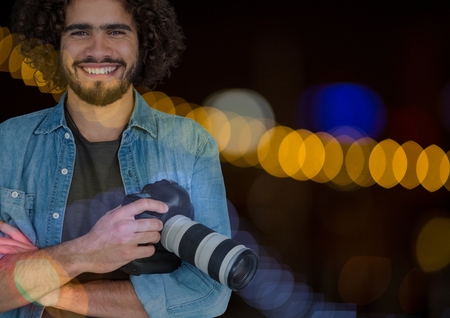Digital composite of Smiling Photographerholding a camera against glowing backgroundの写真素材