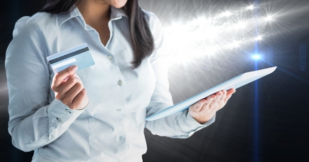 Digital composite of Part of a woman watching a digital tablet screen holding a debit cardの写真素材