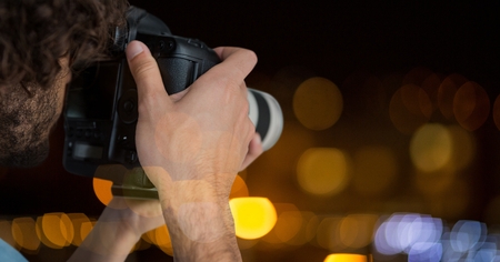 Digital composite of hands holding a camera against glowing background