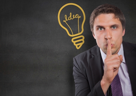 Digital composite of Business man finger on mouth against grey wall with yellow lightbulb graphicの写真素材