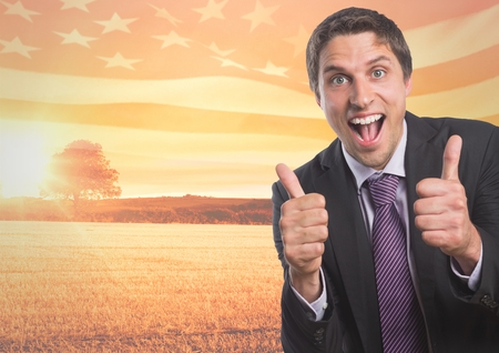 Digital composite of Happy business man with thumbs up against sunset landscapeの写真素材