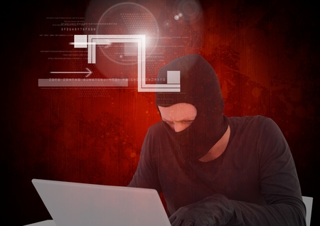 Digital composite of Hacker working on laptop in front of digital red backgroundの写真素材