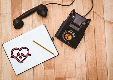 Digital composite of Heart doodle on notepad next to black vintage phoneの写真素材