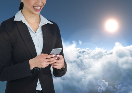 Digital composite of Smiling woman texting in 3D cloudy backgroundの写真素材