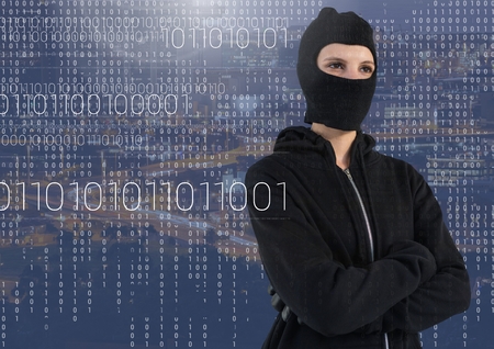 Digital composite of Woman hacker with hood standing on in front of blue digital background