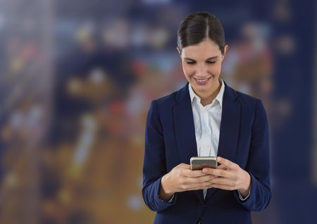Digital composite of Smiling woman texting against city backgroundの写真素材
