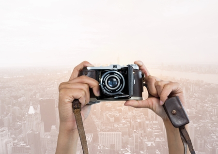 Digital composite of Hands of photographer taking picture against buildings in backgroundの写真素材