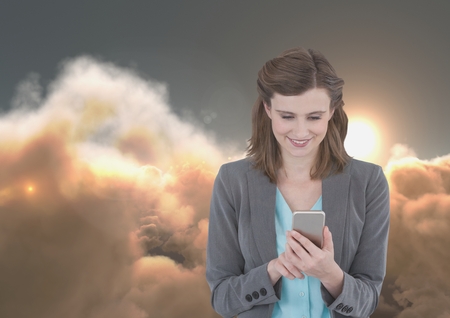Digital composite of Smiling woman texting in 3D cloudy backgroundの写真素材