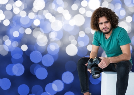 Digital composite of photographer with camera on the hands, sitting. Blue bokeh backgroundの写真素材