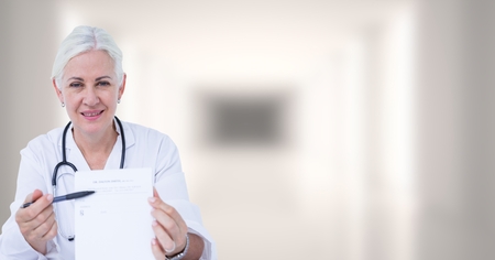 Digital composite of Doctor holding clipboard against blurry white hallwayの写真素材