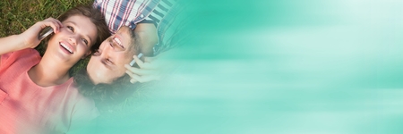 Digital composite of Couple lying on grass with phones and blurry green transitionの写真素材