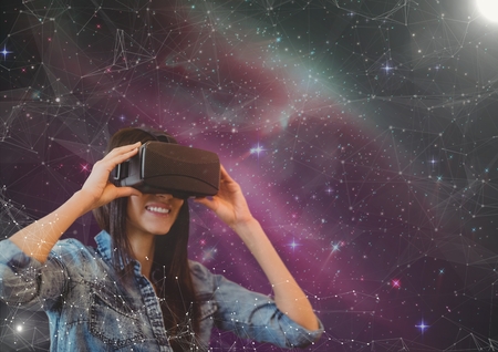 Digital composite of Happy woman in VR headset looking to a pink galaxy background