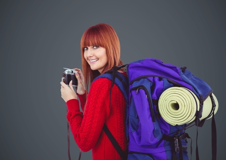 Digital composite of Millennial backpacker with camera against grey backgroundの写真素材
