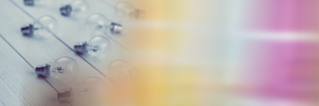 Digital composite of Lightbulbs on wood floor with blurry rainbow transitionの写真素材