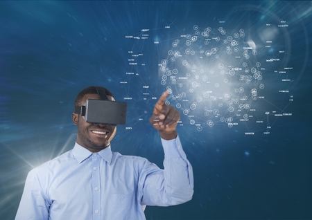 Digital composite of Happy man in VR headset touching interface with flares against blue background
