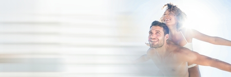 Digital composite of Couple piggy back with flare and blurry white transitionの写真素材