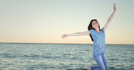 Digital composite of Woman celebrating against water and evening sky 3dの写真素材