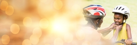Digital composite of Mother fixing daughter's helmet and orange bokeh copy space transitionの写真素材
