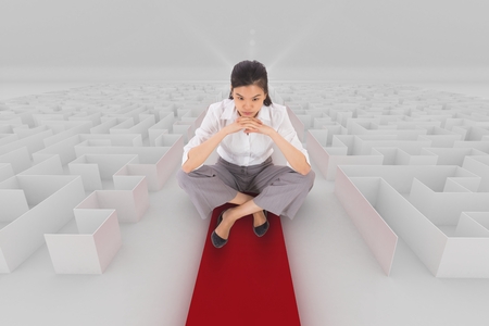 Digital composite of Woman sitting on a 3d maze with an arrowの写真素材