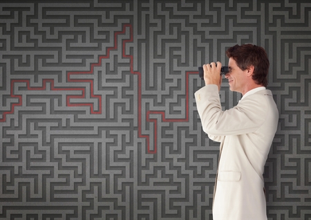 Digital composite of Man looking through binoculars against 3d maze backgroundの写真素材
