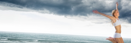 Digital composite of Woman in underwear celebrating on grey beachの写真素材