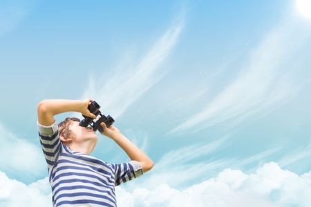 Digital composite of Boy looking through binoculars against skyの写真素材
