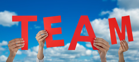 Cropped hand of businesswoman holding letter M against scenic view of blue skyの写真素材
