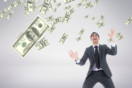 Digital composite of Excited business man looking at money rain against white backgroundの写真素材