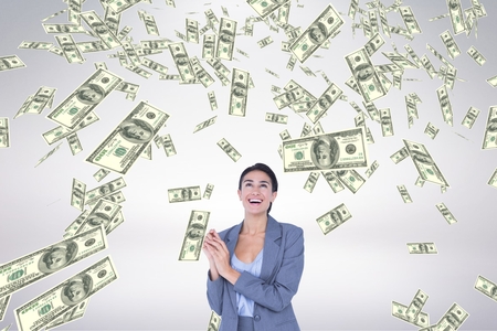 Digital composite of Happy business woman looking at money rain against white backgroundの写真素材