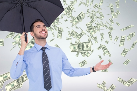 Digital composite of Happy business man under umbrella looking at money rain against white backgroundの写真素材